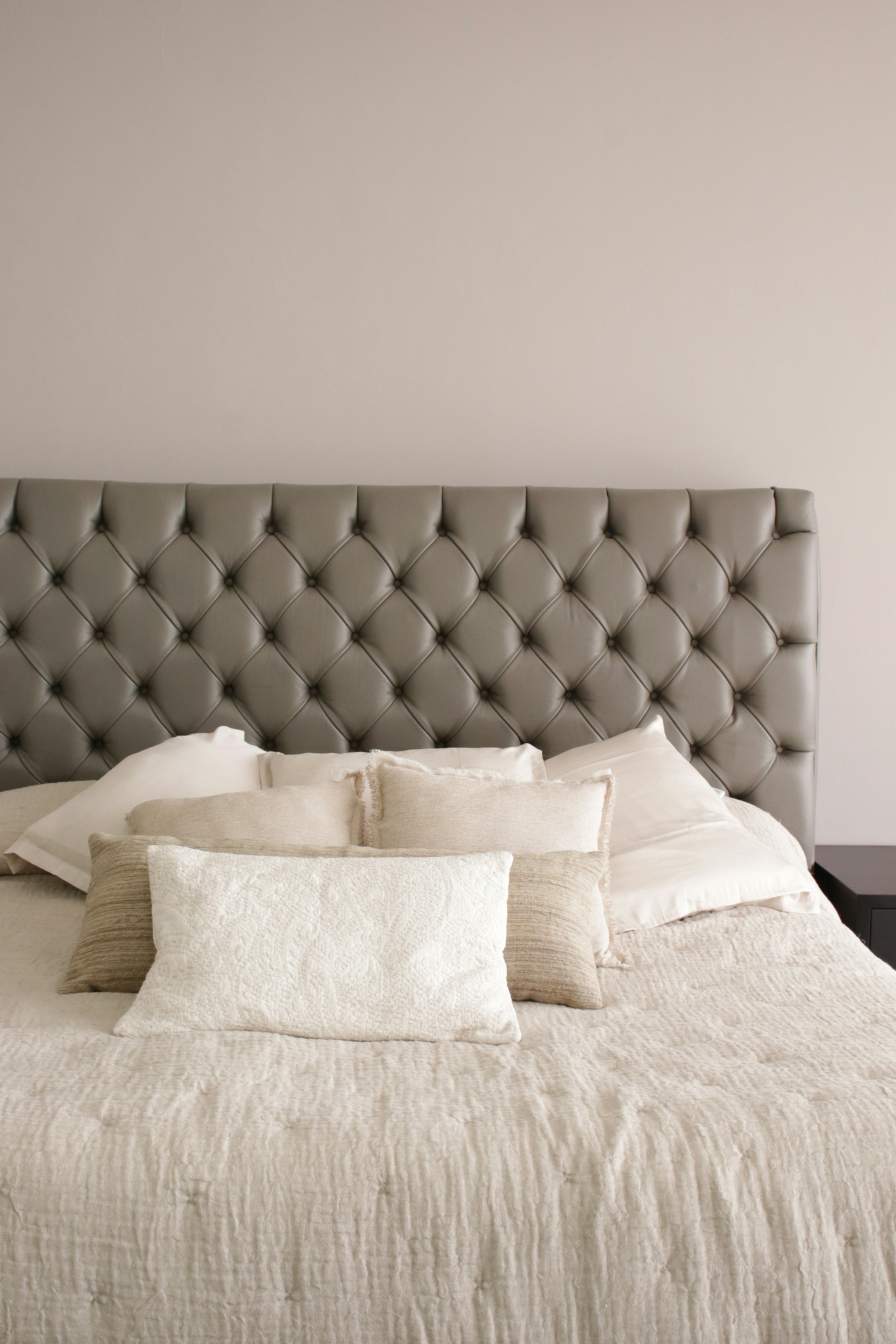 Upholstered grey headboard above a made bed